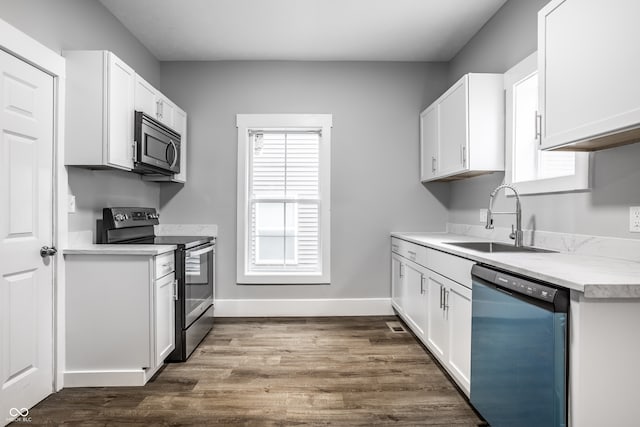 kitchen with dark wood-type flooring, appliances with stainless steel finishes, sink, and white cabinets