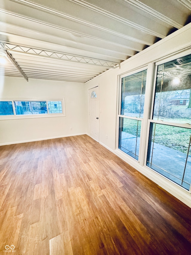 spare room featuring beamed ceiling and wood-type flooring