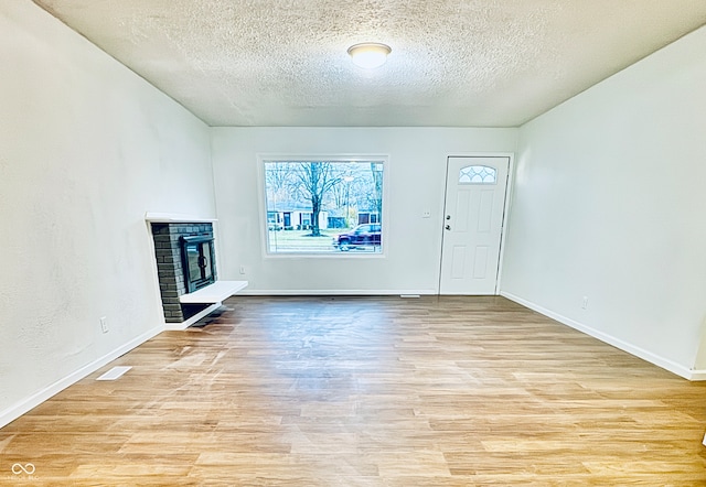 unfurnished living room featuring a textured ceiling and light wood-type flooring