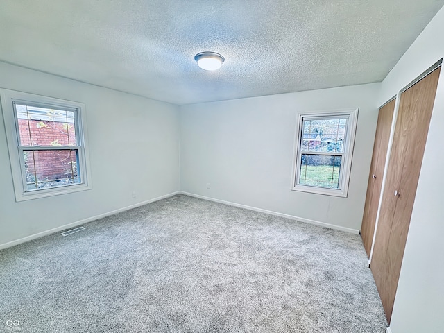 carpeted spare room featuring plenty of natural light and a textured ceiling