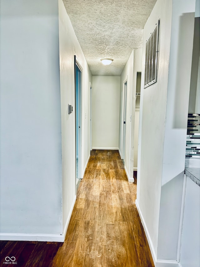 hallway with light hardwood / wood-style floors and a textured ceiling