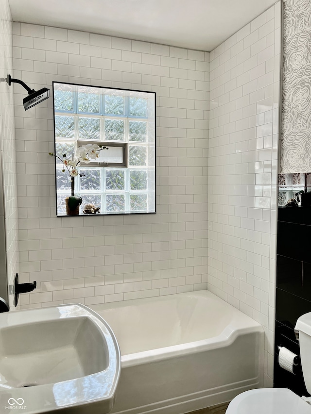 full bathroom featuring toilet, tiled shower / bath combo, and sink