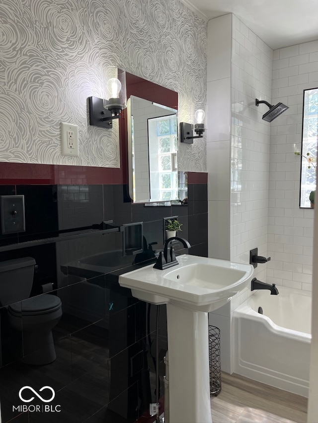 full bathroom featuring tiled shower / bath, sink, wood-type flooring, toilet, and tile walls