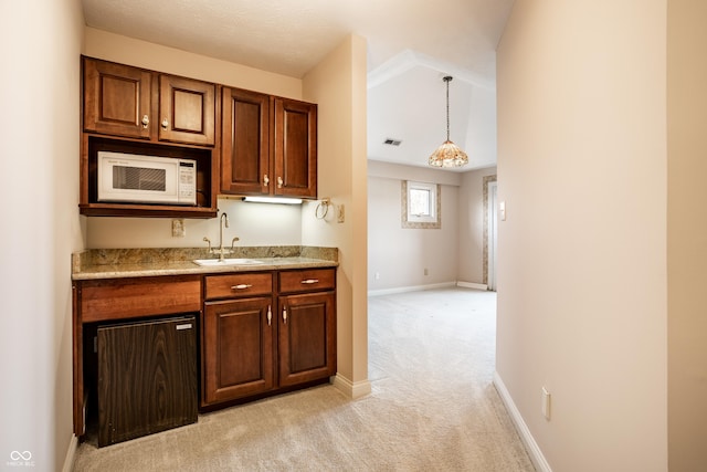 kitchen featuring light carpet, decorative light fixtures, light stone countertops, and sink