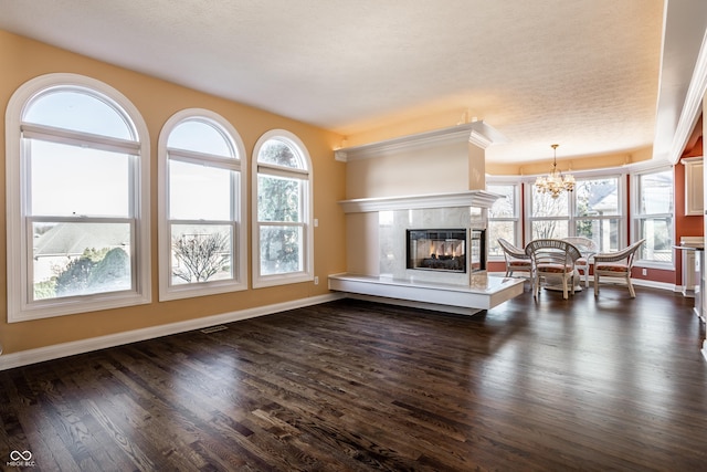 unfurnished living room featuring a chandelier, a textured ceiling, and dark hardwood / wood-style floors