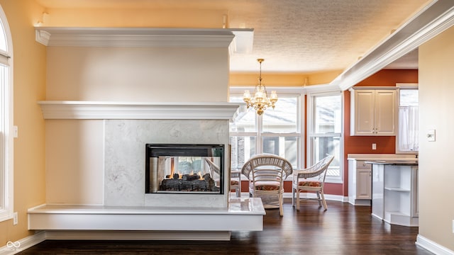 living room with ornamental molding, a textured ceiling, a premium fireplace, dark hardwood / wood-style flooring, and a chandelier