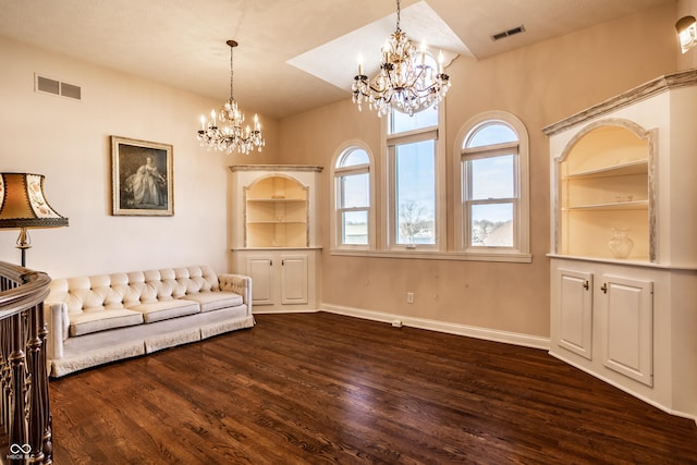 unfurnished room with built in shelves, dark hardwood / wood-style floors, and a notable chandelier