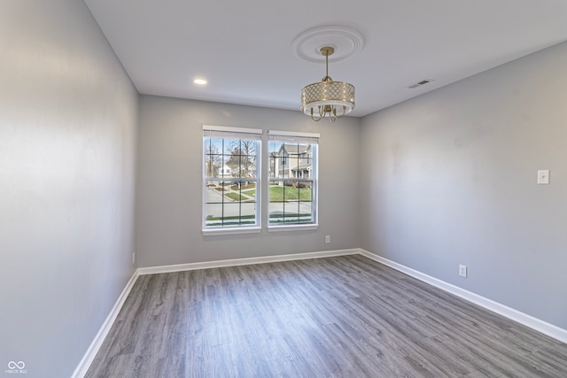 spare room featuring hardwood / wood-style flooring and a notable chandelier