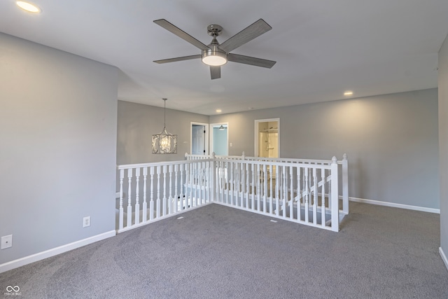 carpeted spare room with ceiling fan with notable chandelier