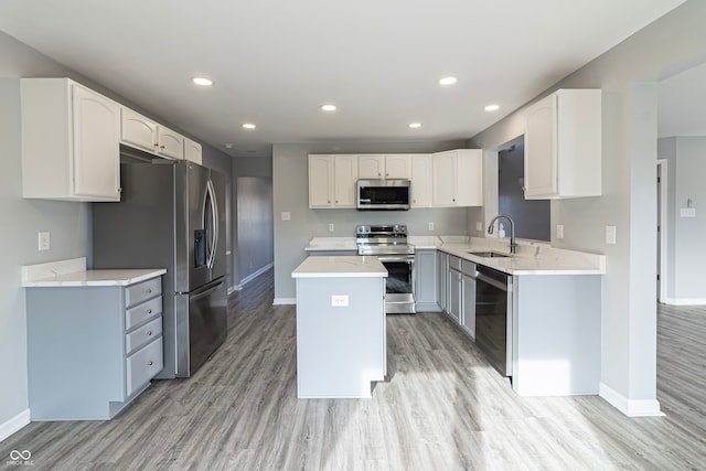 kitchen featuring appliances with stainless steel finishes, sink, white cabinets, light hardwood / wood-style floors, and a kitchen island