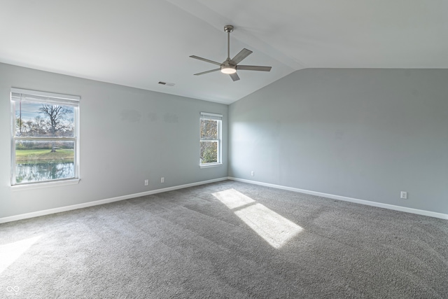 carpeted spare room with ceiling fan, a wealth of natural light, and vaulted ceiling