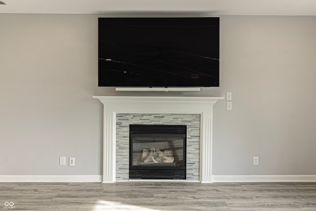 interior details with a tiled fireplace and hardwood / wood-style flooring