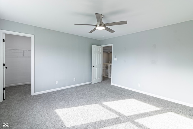 unfurnished bedroom with carpet, a closet, a spacious closet, and ceiling fan