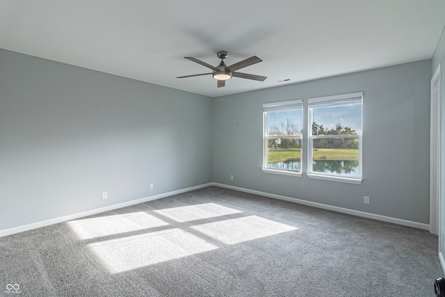 spare room featuring carpet flooring, a water view, and ceiling fan