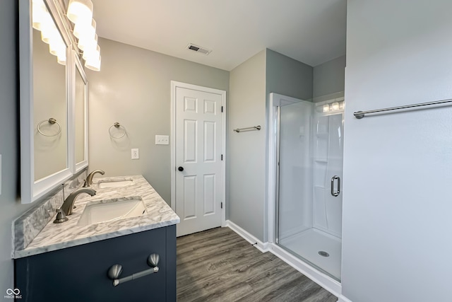 bathroom featuring wood-type flooring, vanity, and a shower with shower door