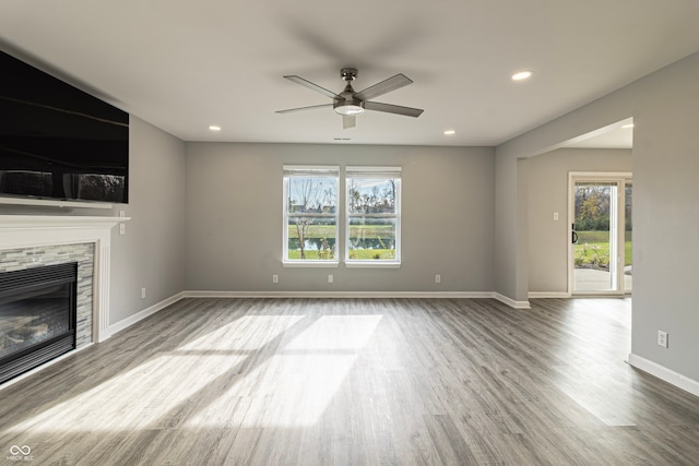 unfurnished living room featuring a tile fireplace, wood-type flooring, and a healthy amount of sunlight