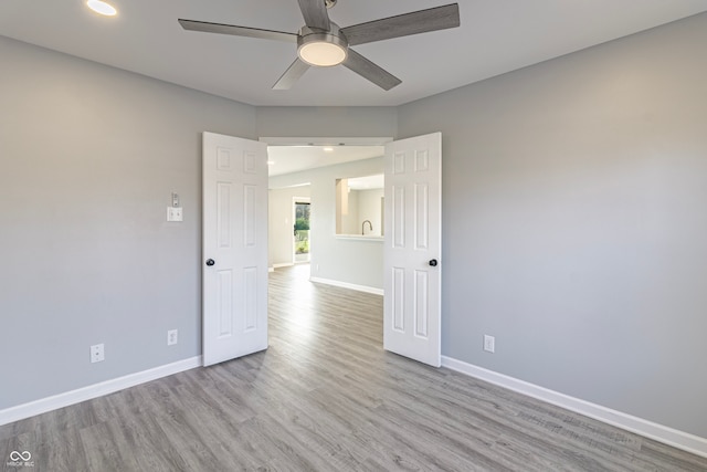 spare room with ceiling fan and light wood-type flooring