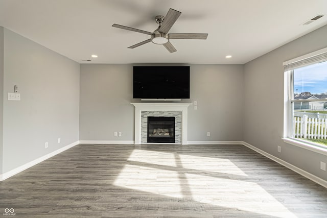 unfurnished living room featuring hardwood / wood-style floors, ceiling fan, and a tiled fireplace