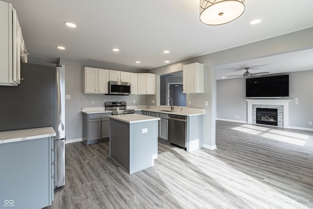 kitchen featuring gray cabinetry, stainless steel appliances, hardwood / wood-style floors, a fireplace, and a kitchen island