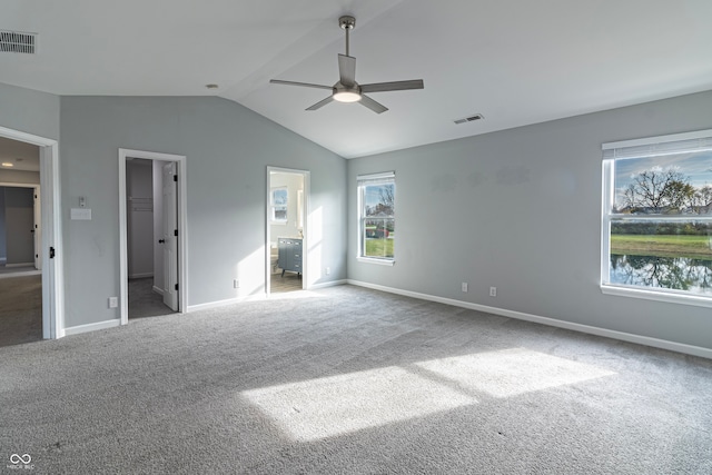 unfurnished bedroom with carpet, ceiling fan, connected bathroom, and vaulted ceiling