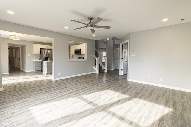 unfurnished living room featuring ceiling fan, sink, and light hardwood / wood-style floors