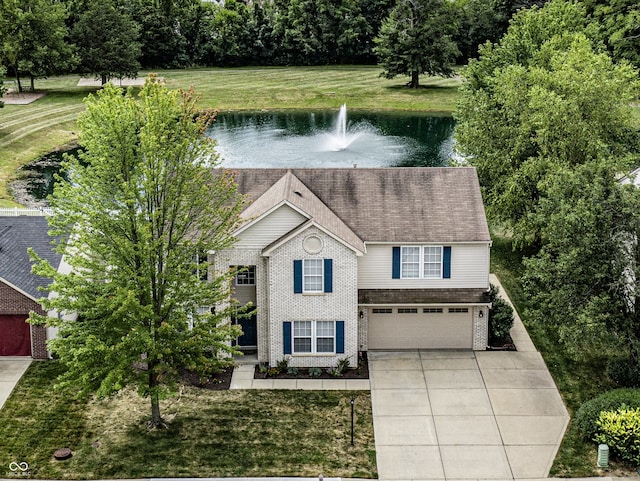 view of front of house featuring a garage, a water view, and a front lawn