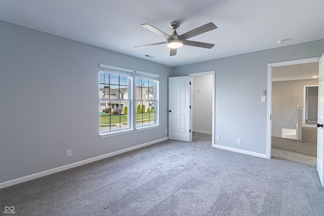 unfurnished bedroom featuring carpet flooring, a walk in closet, a closet, and ceiling fan