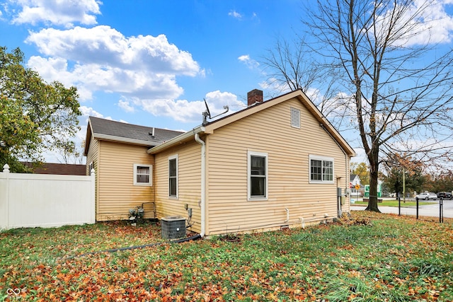 rear view of house with central air condition unit and a yard