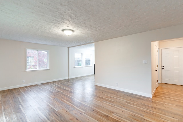 unfurnished room featuring a textured ceiling and light hardwood / wood-style flooring