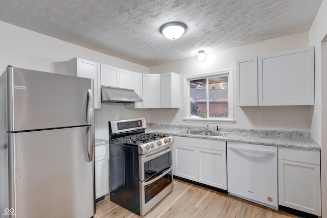 kitchen featuring extractor fan, appliances with stainless steel finishes, sink, light hardwood / wood-style floors, and white cabinets