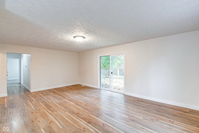 empty room with light hardwood / wood-style floors and a textured ceiling