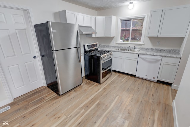 kitchen featuring stainless steel appliances, a textured ceiling, sink, ventilation hood, and light hardwood / wood-style flooring