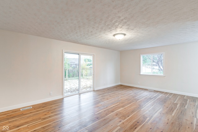 unfurnished room featuring a textured ceiling, light hardwood / wood-style flooring, and a healthy amount of sunlight