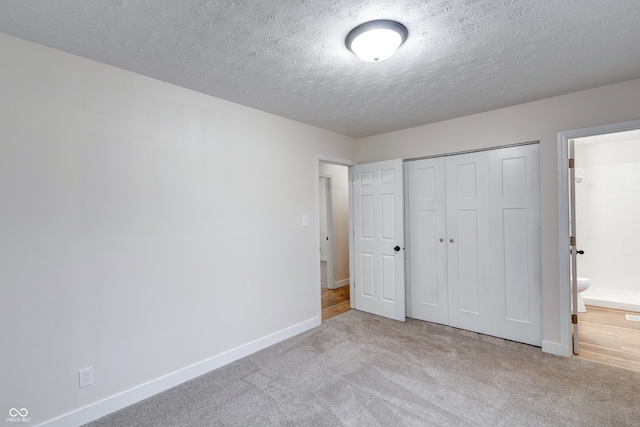 unfurnished bedroom with ensuite bathroom, light colored carpet, and a closet