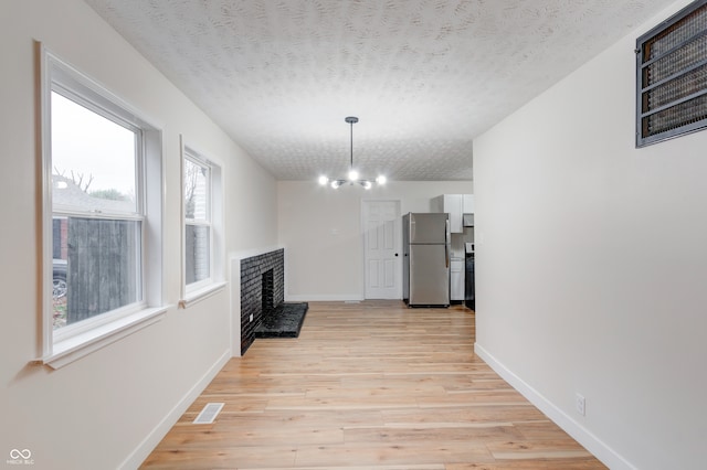 interior space with light wood-type flooring, a chandelier, and a textured ceiling