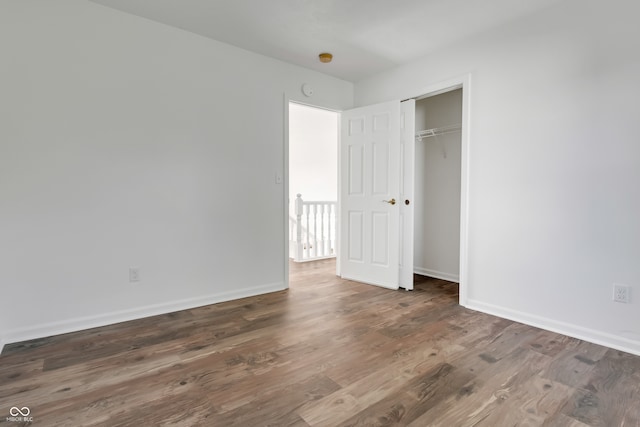 unfurnished bedroom with dark wood-type flooring and a closet