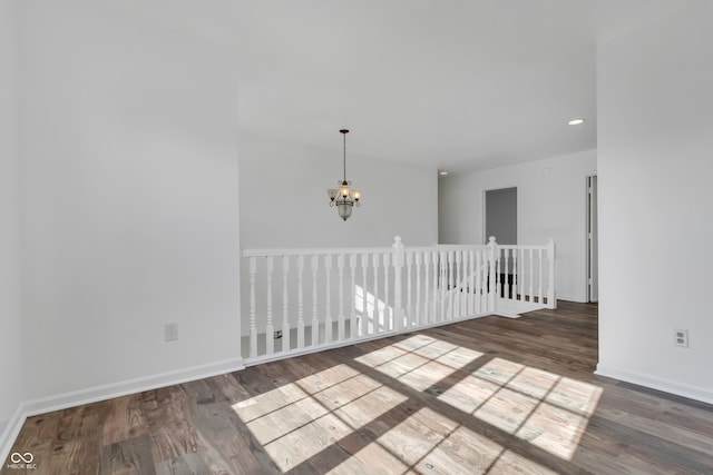 unfurnished room featuring an inviting chandelier and dark hardwood / wood-style floors