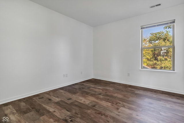 spare room featuring dark wood-style flooring and baseboards