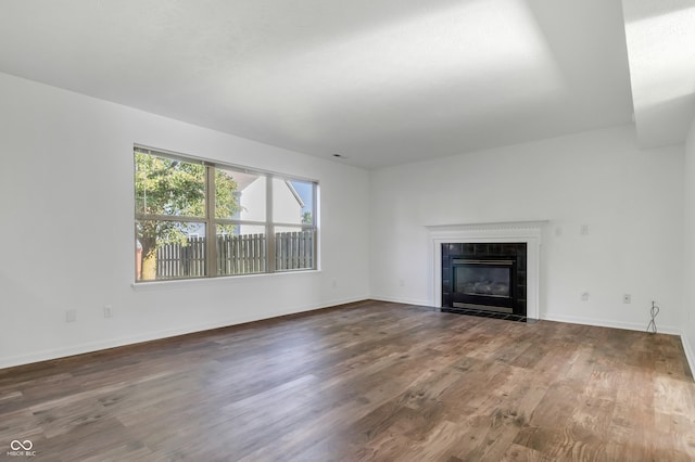 unfurnished living room featuring wood finished floors, a tiled fireplace, and baseboards