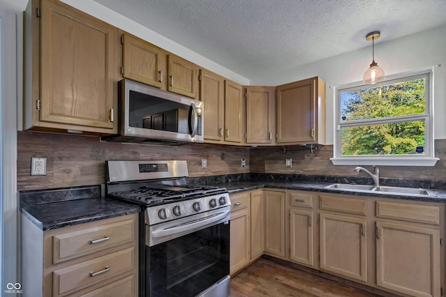 kitchen featuring stainless steel appliances, a sink, decorative backsplash, a textured ceiling, and dark wood-style flooring