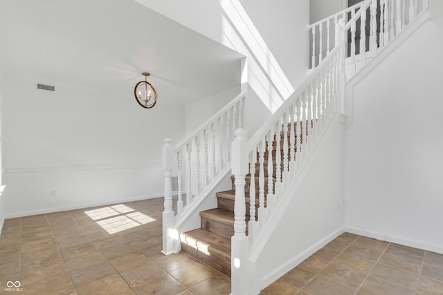 stairs featuring a chandelier, stone finish floors, and baseboards