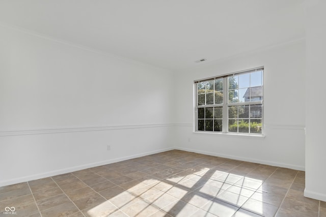empty room with ornamental molding, baseboards, and light tile patterned floors