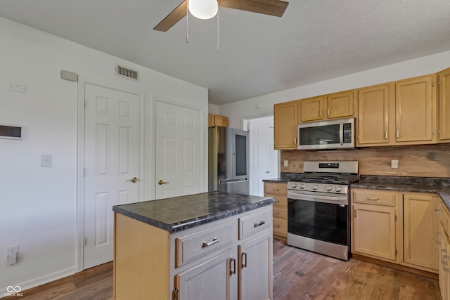 kitchen with tasteful backsplash, stainless steel appliances, hardwood / wood-style floors, ceiling fan, and a center island