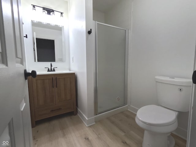 bathroom featuring hardwood / wood-style flooring, a shower with shower door, vanity, and toilet