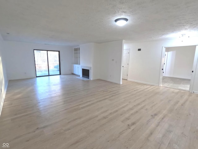 unfurnished living room featuring light hardwood / wood-style floors and a textured ceiling