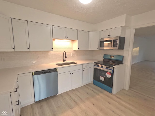 kitchen with light wood-type flooring, white cabinets, sink, and stainless steel appliances