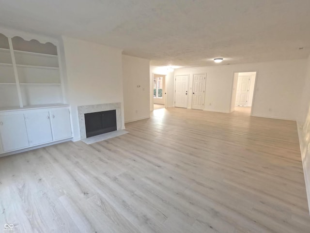 unfurnished living room featuring light hardwood / wood-style flooring and built in shelves