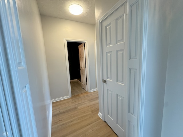 hall featuring a textured ceiling and light hardwood / wood-style flooring