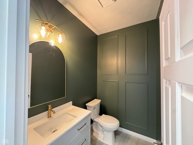 bathroom featuring toilet, vanity, and a textured ceiling