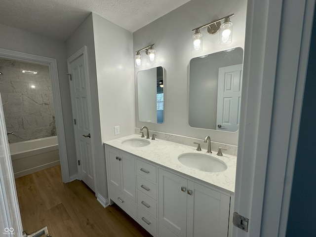 bathroom featuring a textured ceiling, vanity, hardwood / wood-style flooring, and tiled shower / bath combo